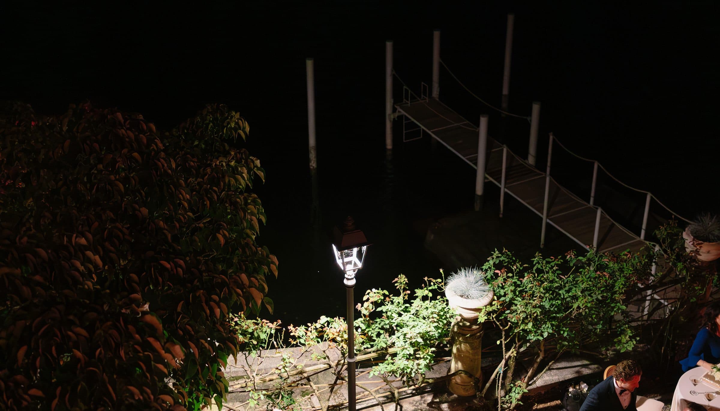 A night garden party under lamplight, seen from a balcony above